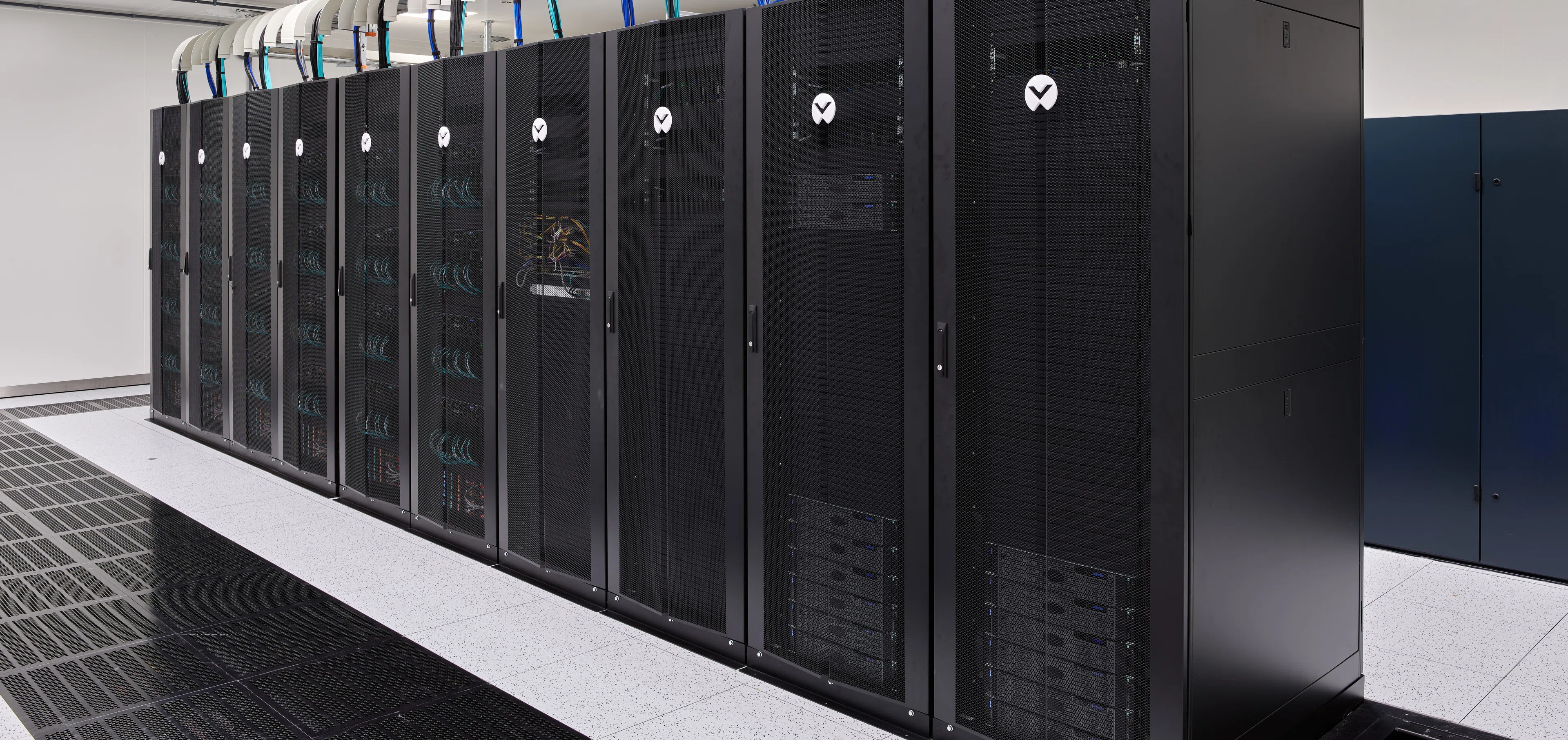 A row of supercomputer racks along the cold aisle of a PHOENIQS data center hall